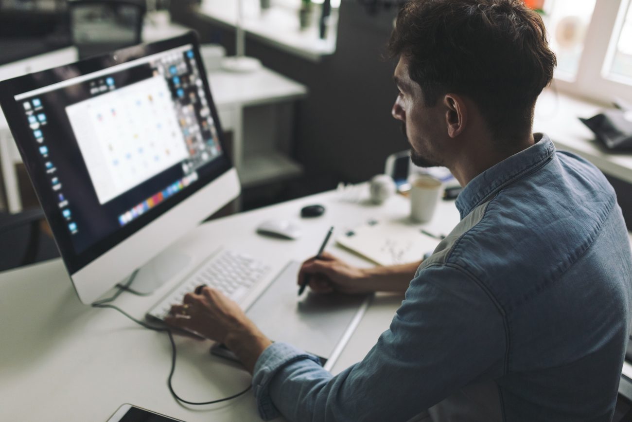 Modern designer sitting in front of computer and working in office