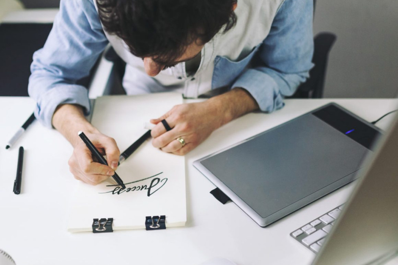 Designer at work in office. Man drawing in note pad