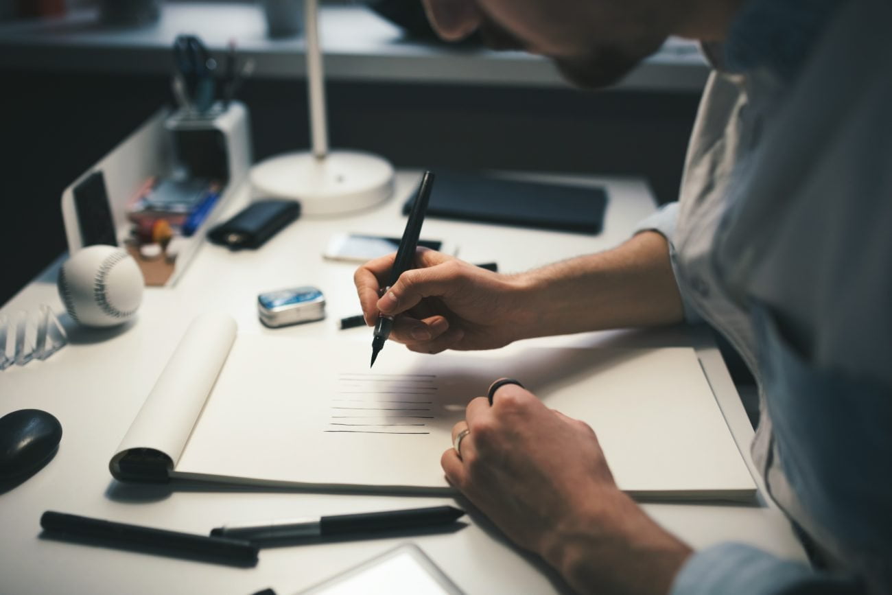 Designer at work in office. Man drawing in note pad